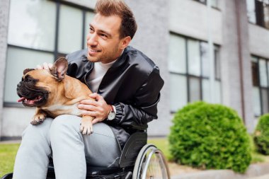 Gülümseyen engelli adam şehir caddesinde buldog oynatıyor.
