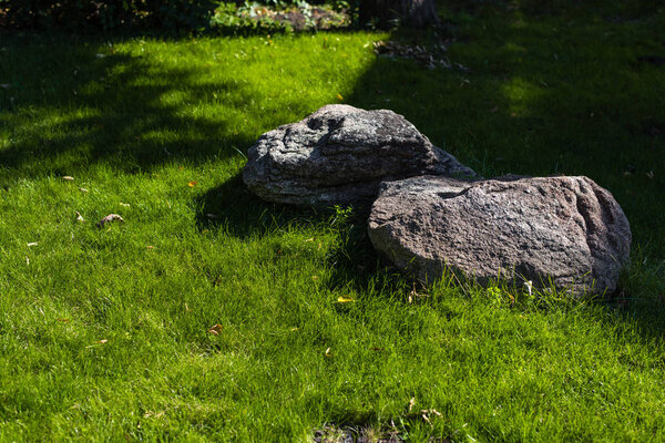 Two stones with sunlight on green grass of lawn 