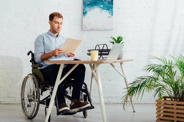 Uomo Sulla Sedia Rotelle Che Guarda Documenti Sul Posto Lavoro — Foto Stock