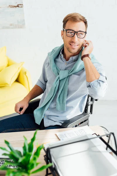 Homem Sorridente Cadeira Rodas Usando Fones Ouvido Sem Fio Mesa — Fotografia de Stock