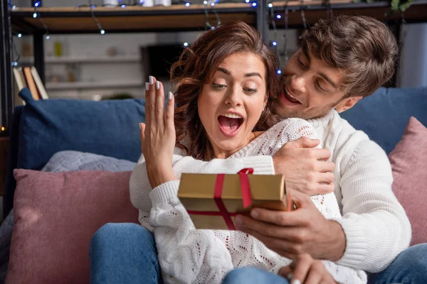 Handsome Boyfriend Giving Present Shocked Girlfriend Sweater Christmastime — Stock Photo, Image