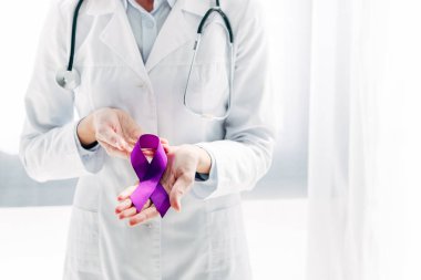 Klinikte elinde mor kurdele tutan beyaz önlüklü bir doktor. 