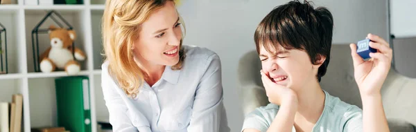 Plano Panorámico Niño Con Dislexia Sosteniendo Bloque Construcción Sonriente Psicólogo — Foto de Stock