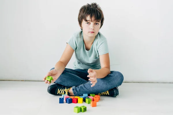 Niño Con Dislexia Sentado Suelo Con Bloques Construcción Sobre Fondo — Foto de Stock