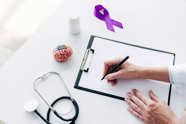 cropped view of doctor writing on clipboard with pen 