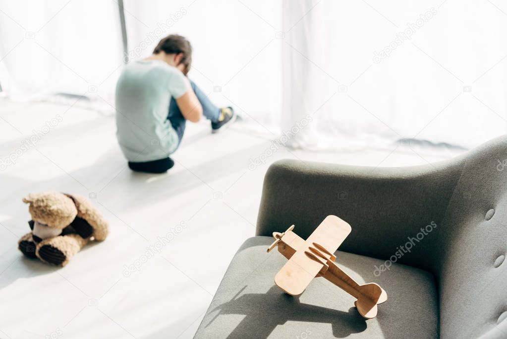 selective focus of wooden plane on armchair and kid with dyslexia on background 