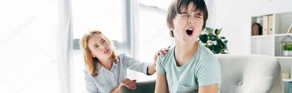 panoramic shot of kid with dyslexia screaming and child psychologist looking at him 