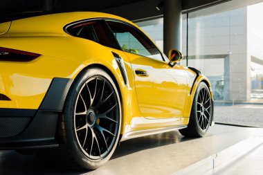 KYIV, UKRAINE - OCTOBER 7, 2019: sunshine on yellow luxury porshe in car showroom  clipart