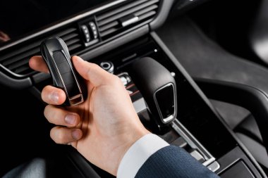 Kyiv, Ukrayna - 7 Ekim 2019: Porshe 'de vites kutusunun yanında arabanın anahtarını tutan sürücünün kırpılmış görüntüsü 