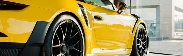 KYIV, UKRAINE - OCTOBER 7, 2019: panoramic shot of yellow luxury porshe in car showroom 