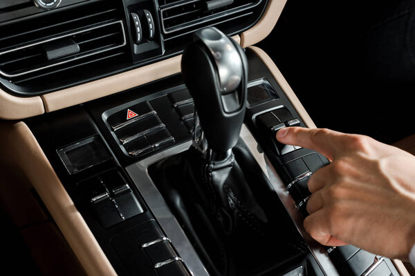 КИЕВ, УКРАИНА - 7 ОКТЯБРЯ 2019: обрезанный вид человека, указывающего пальцем на кнопку возле переключения передач в порше
  