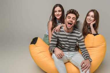 Neşeli arkadaşlar çöp tenekesinde birlikte oturuyorlar, gri renkte izole edilmişler.
