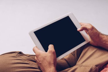 Gri ekranda izole edilmiş boş ekranlı dijital tablet kullanan adamın kısmi görünümü