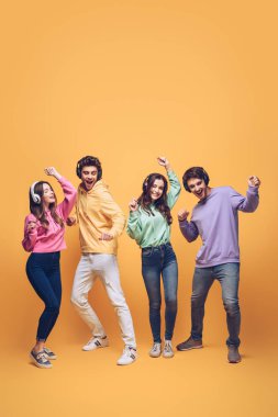 pozitif arkadaşlar kulaklıkla müzik dinliyorlar ve birlikte dans ediyorlar, sarıda.