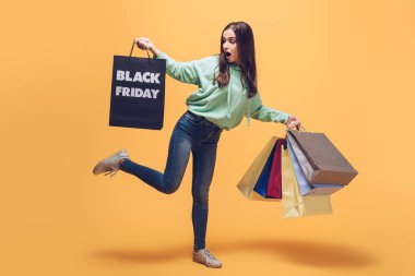 shocked girl holding shopping bags on black friday, on yellow clipart