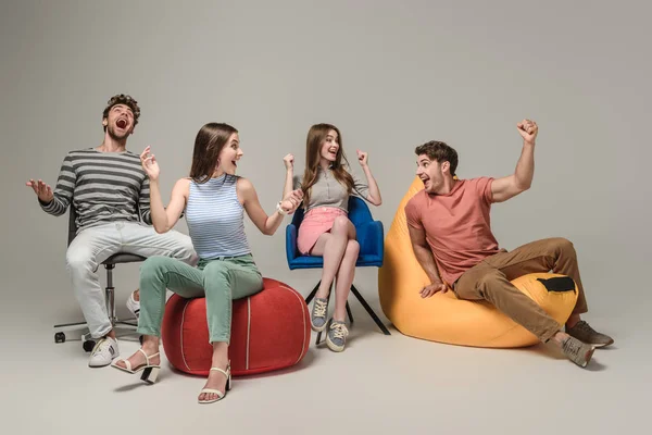 Vrolijke Vrienden Juichen Zitten Verschillende Stoelen Grijs — Stockfoto