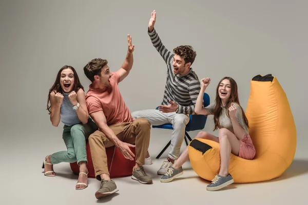 Amis Excités Donnant Highfive Assis Sur Différentes Chaises Sur Gris — Photo