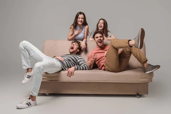 Glückliche Freunde Lachen Und Entspannen Auf Dem Sofa Auf Grau — Stockfoto
