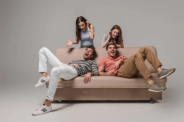 Jóvenes Amigos Riendo Relajándose Sofá Gris — Foto de Stock