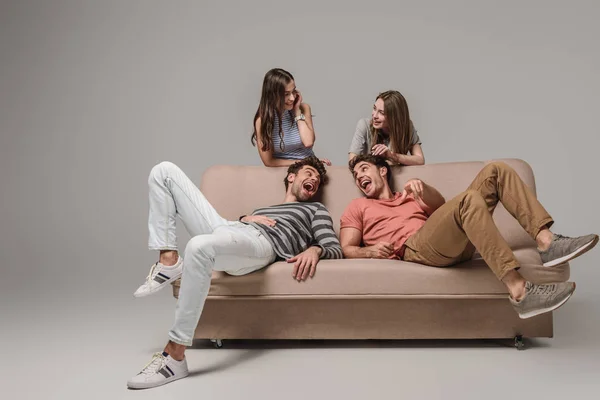 Young Friends Laughing Sitting Sofa Grey — Stock Photo, Image