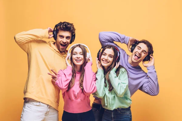 Smiling Friends Listening Music Headphones Dancing Together Isolated Yellow — Stock Photo, Image