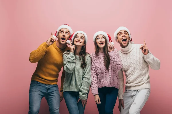 Amigos Felices Suéteres Sombreros Santa Señalando Hacia Arriba Aislados Rosa —  Fotos de Stock