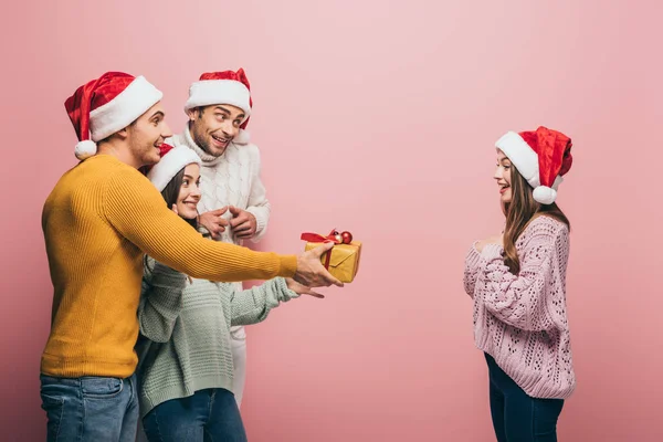 Fröhliche Freunde Weihnachtsmützen Die Einem Mädchen Ein Weihnachtsgeschenk Machen Isoliert — Stockfoto
