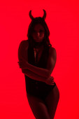 silueta sexy ženy v kostýmu ďábla, izolovaná na červené