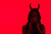 silueta svůdné ženy v kostýmu ďábla, izolovaná na červené