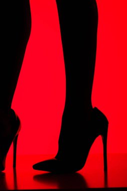 Kırmızıda soyutlanmış, topuklu ayakkabılı seksi bir kadın silueti.