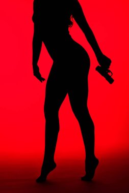 Kırmızıda izole edilmiş silah tutan suçlu seksi kadın silueti.
