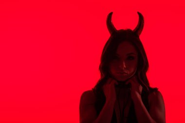 Şeytan kostümlü baştan çıkarıcı kadın silueti, kırmızı üzerine izole edilmiş.