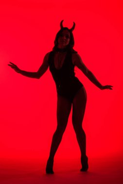 Şeytan kostümlü çekici seksi kadın silueti, kırmızı üzerine izole edilmiş.