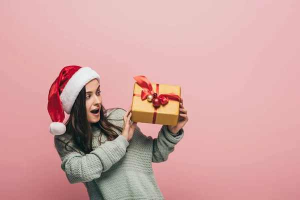Überraschte Frau Pullover Und Weihnachtsmütze Mit Weihnachtsgeschenk Isoliert Auf Rosa — Stockfoto