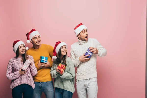 Glückliche Freunde Weihnachtsmützen Mit Weihnachtsgeschenken Isoliert Auf Rosa — Stockfoto