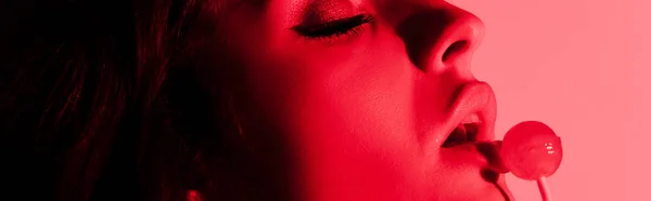 パノラマ撮影の魅力的なセクシー女の子食べるロリポップで赤い光 — ストック写真