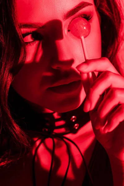赤い光の中でロリポップを食べる美しい情熱的な女性 — ストック写真