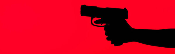 cropped view of silhouette of criminal woman holding gun isolated on red, panoramic shot