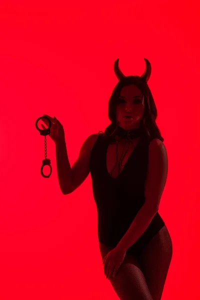 Silhueta Sexy Menina Diabo Traje Segurando Algemas Isolado Vermelho — Fotografia de Stock