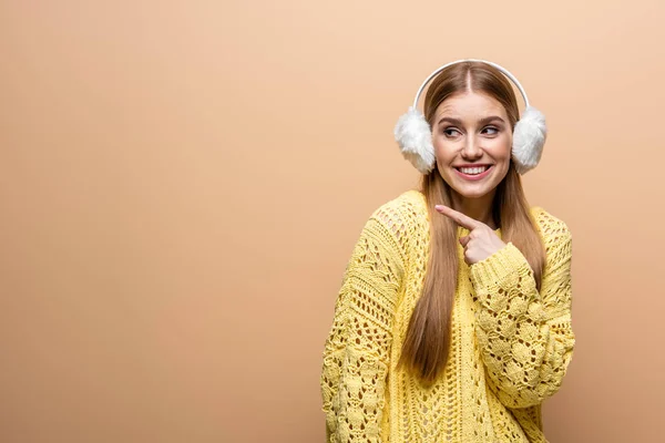 Beautiful Smiling Woman Pointing Yellow Sweater Earmuffs Isolated Beige — Stock Photo, Image