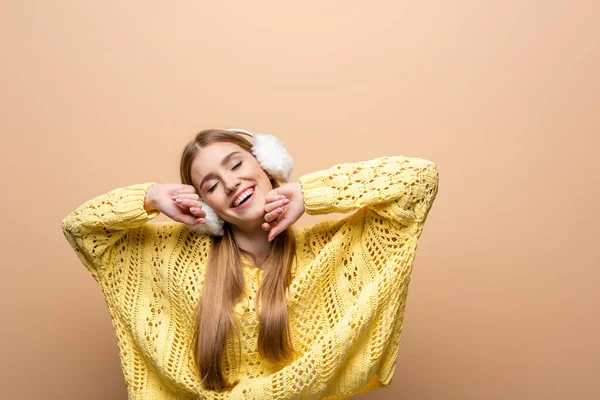 Smiling Dreamy Woman Closed Eyes Yellow Sweater Earmuffs Isolated Beige — Stock Photo, Image