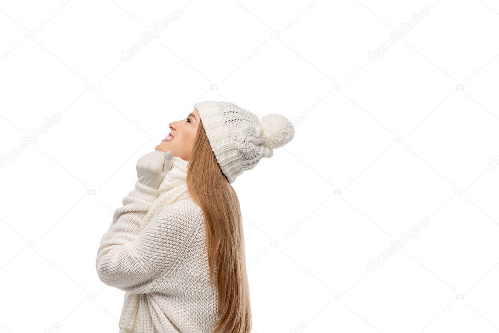 smiling woman warming up in white knitted sweater, scarf and hat, isolated on white