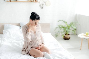 attractive pregnant woman in nightie having nausea in bedroom clipart