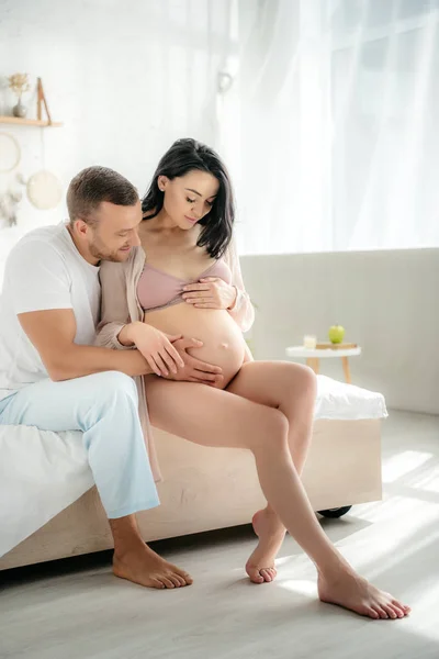 Marido Feliz Abrazando Esposa Embarazada Mientras Está Sentado Cama Dormitorio — Foto de Stock