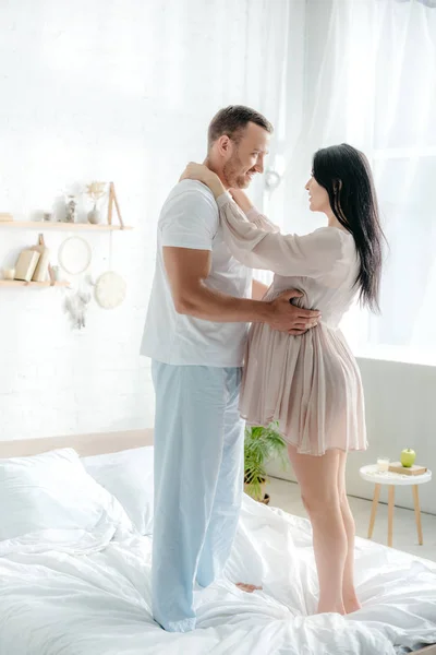 Feliz Pareja Embarazada Abrazándose Mientras Está Pie Cama Dormitorio — Foto de Stock