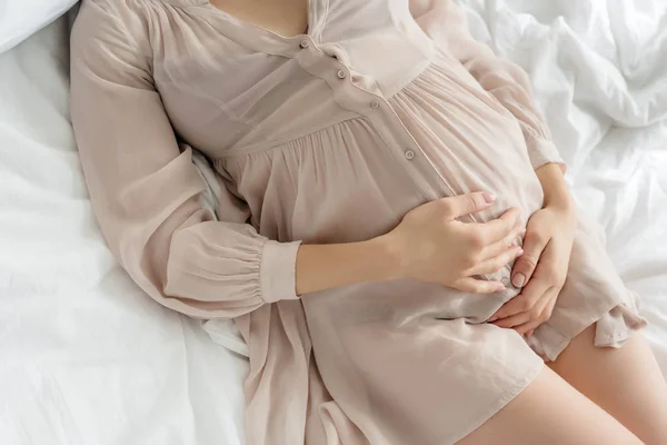 Yatakta Yatarken Karnına Dokunan Gecelikli Hamile Kadın Görüntüsü — Stok fotoğraf