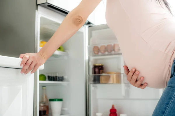 Cropped View Pregnant Woman Holding Belly Looking Opened Fridge Kitchen — Stock Photo, Image