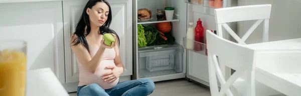 Tiro Panorâmico Mulher Grávida Segurando Maçã Enquanto Sentado Chão Cozinha — Fotografia de Stock