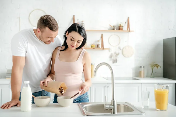 快乐的怀孕夫妇 厨房里有谷类 牛奶和橙汁 — 图库照片