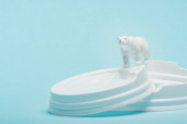 Toy jegesmedve műanyag kávés fedél kék alapon, ökológiai probléma koncepció